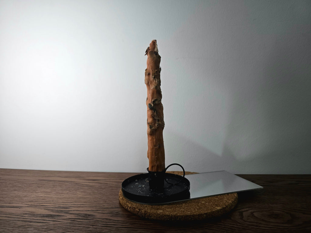 Decorated Candle on a black stand with a white plate on a wooden surface