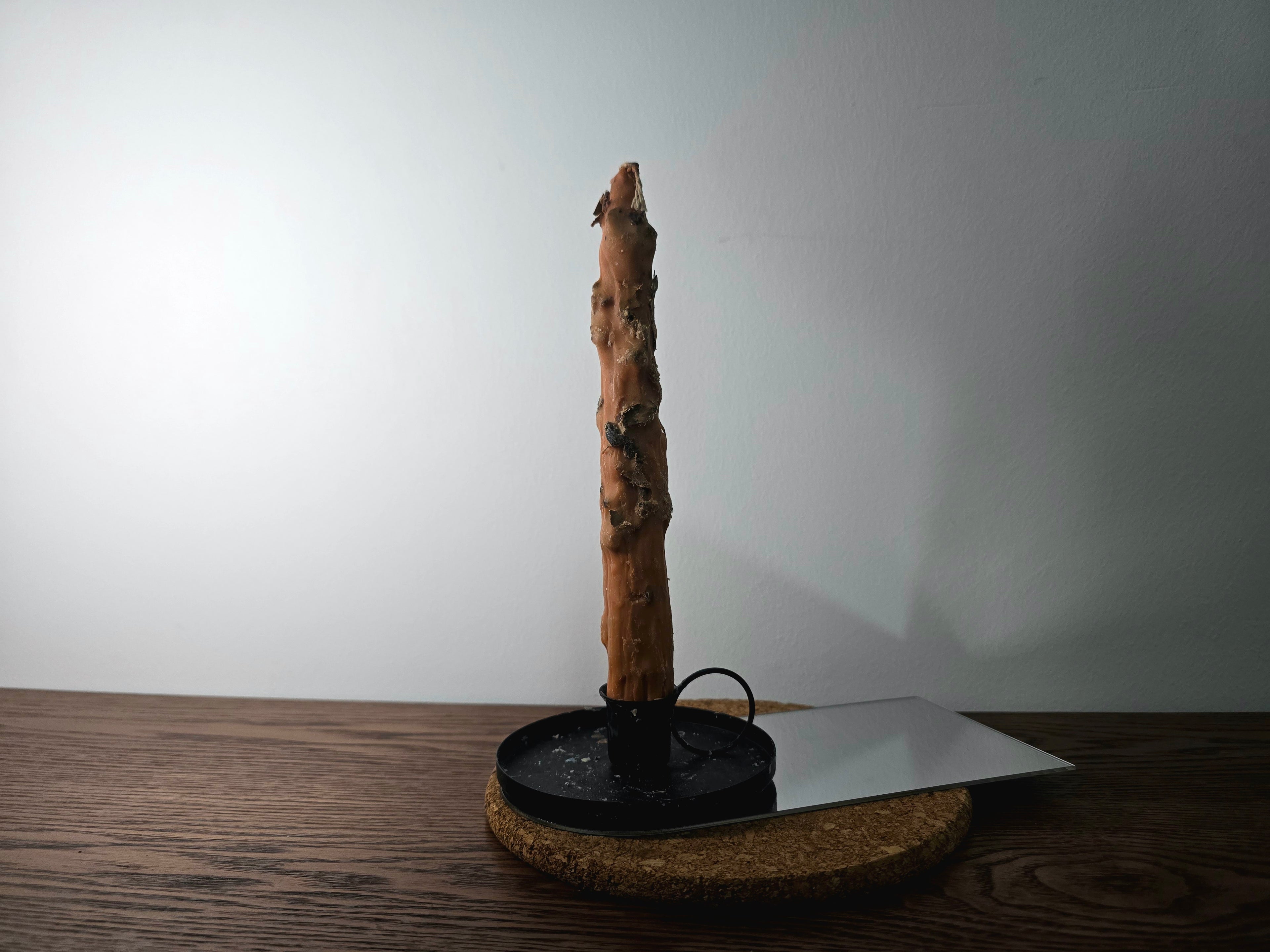 Decorated Candle on a black stand with a white plate on a wooden surface