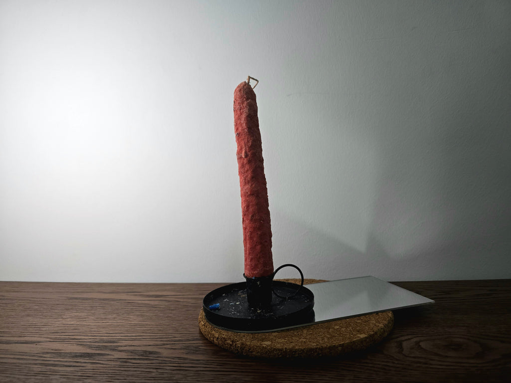 Decorated Candle on a black stand with a white plate on a wooden surface