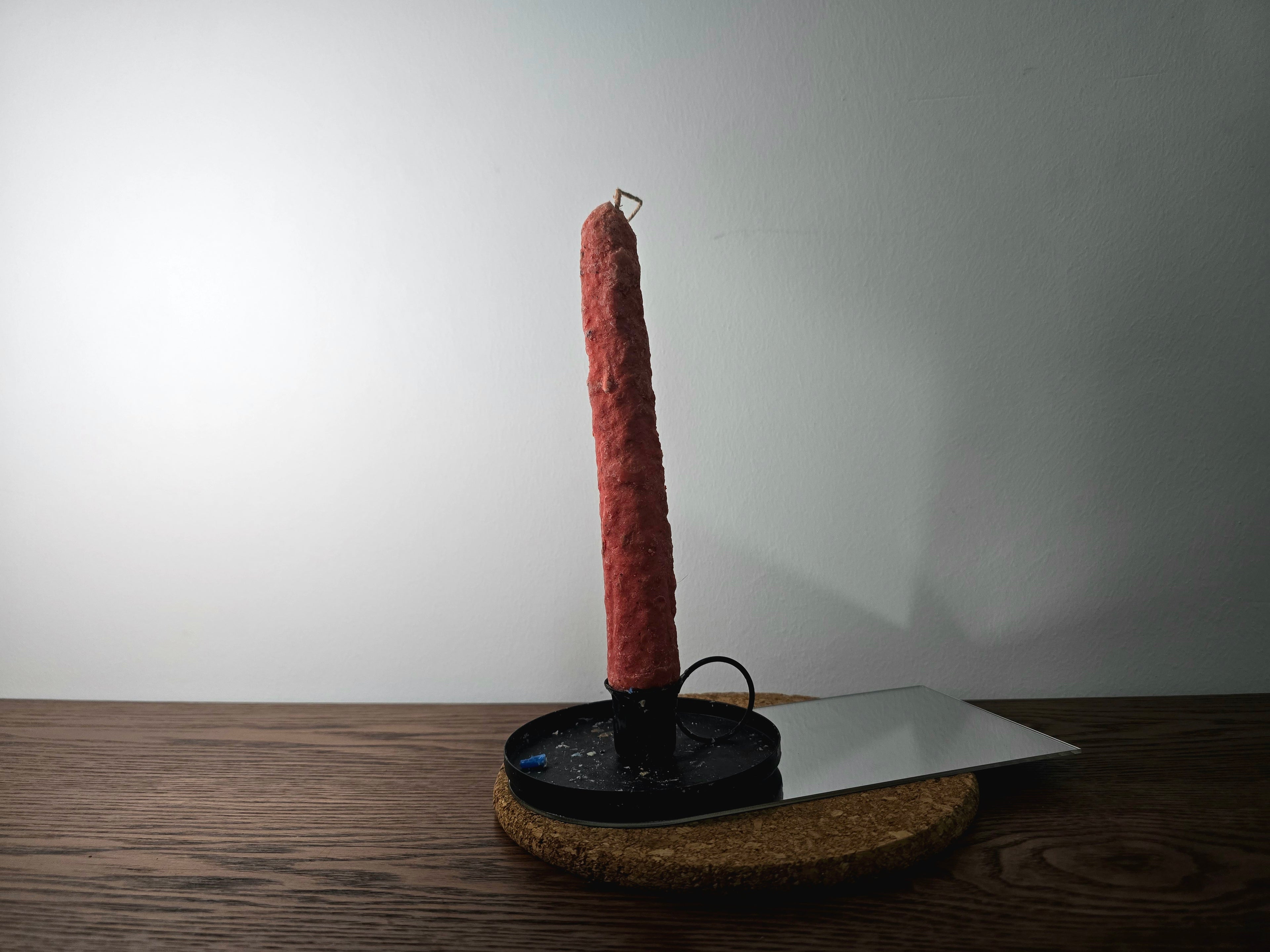 Decorated Candle on a black stand with a white plate on a wooden surface