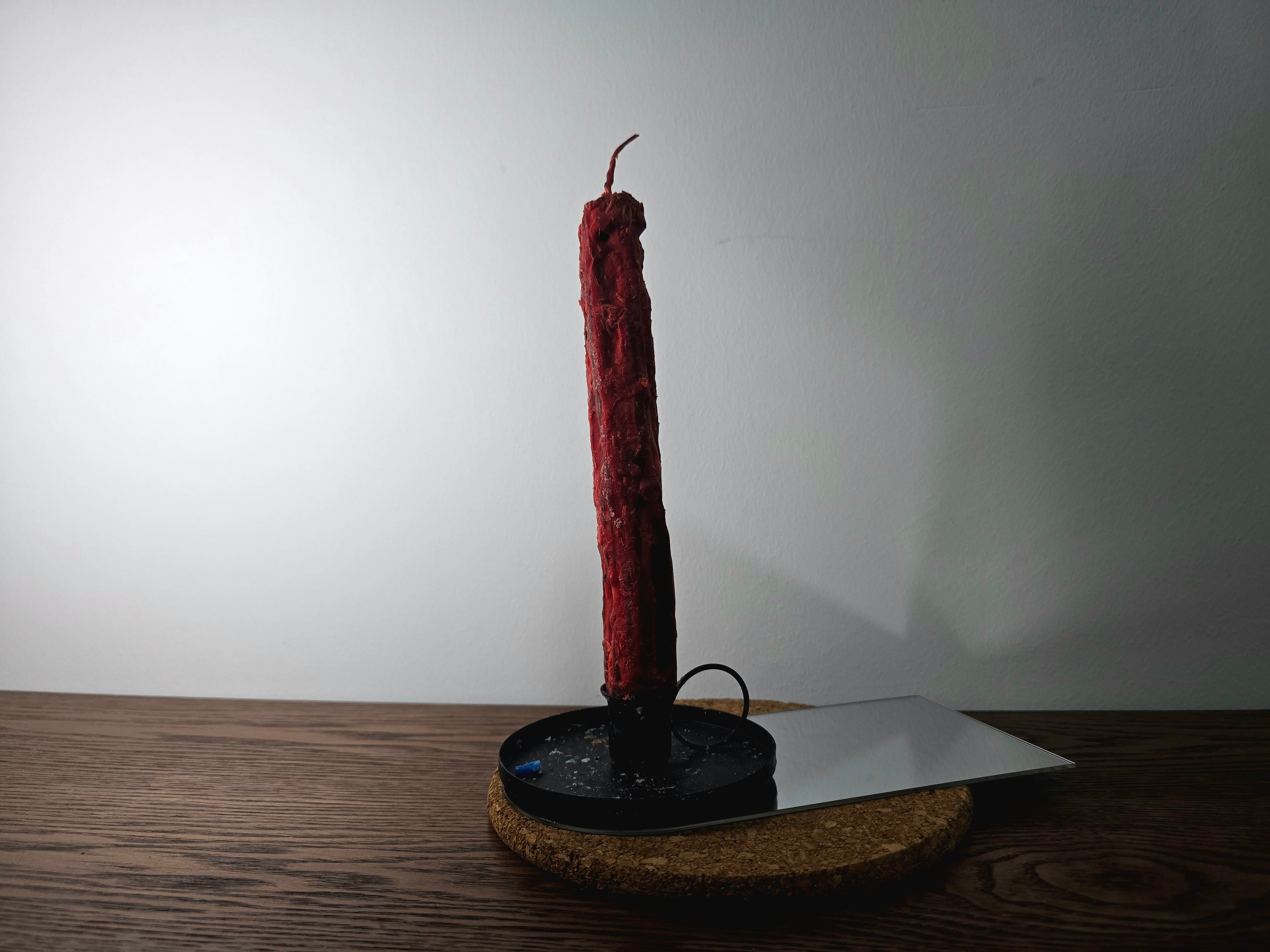 Decorated Candle on a black stand with a white plate on a wooden surface