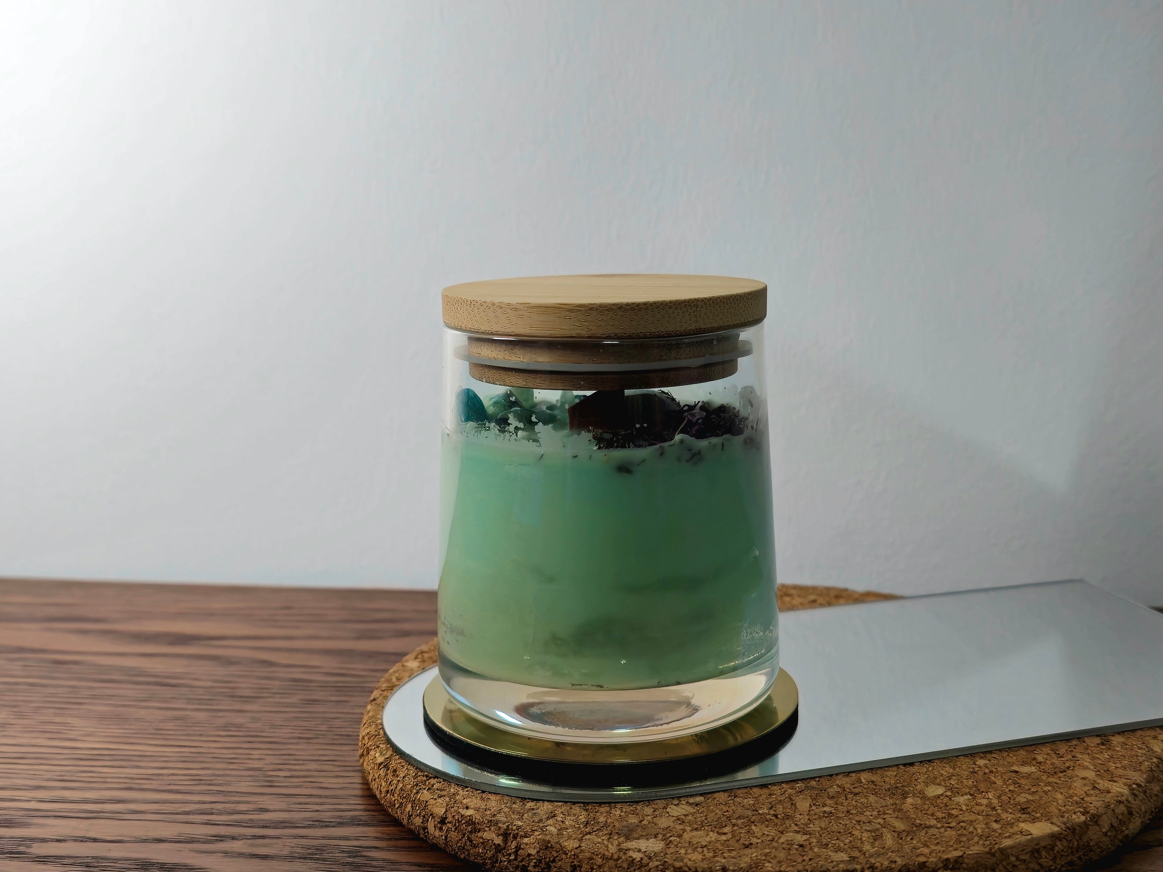 Candle Glass jar with a wooden lid on a cork base against a white wall