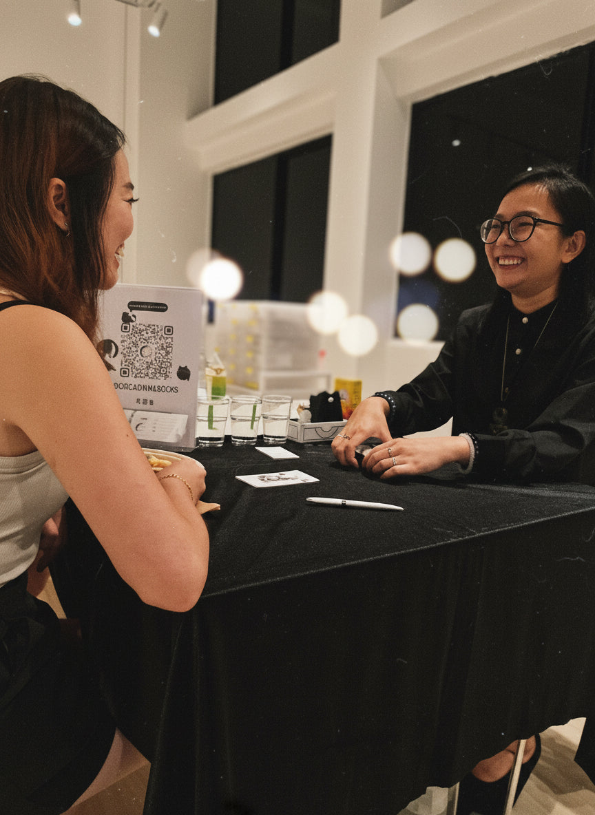 Two women sitting at a table with a black tablecloth, engaged in divination.