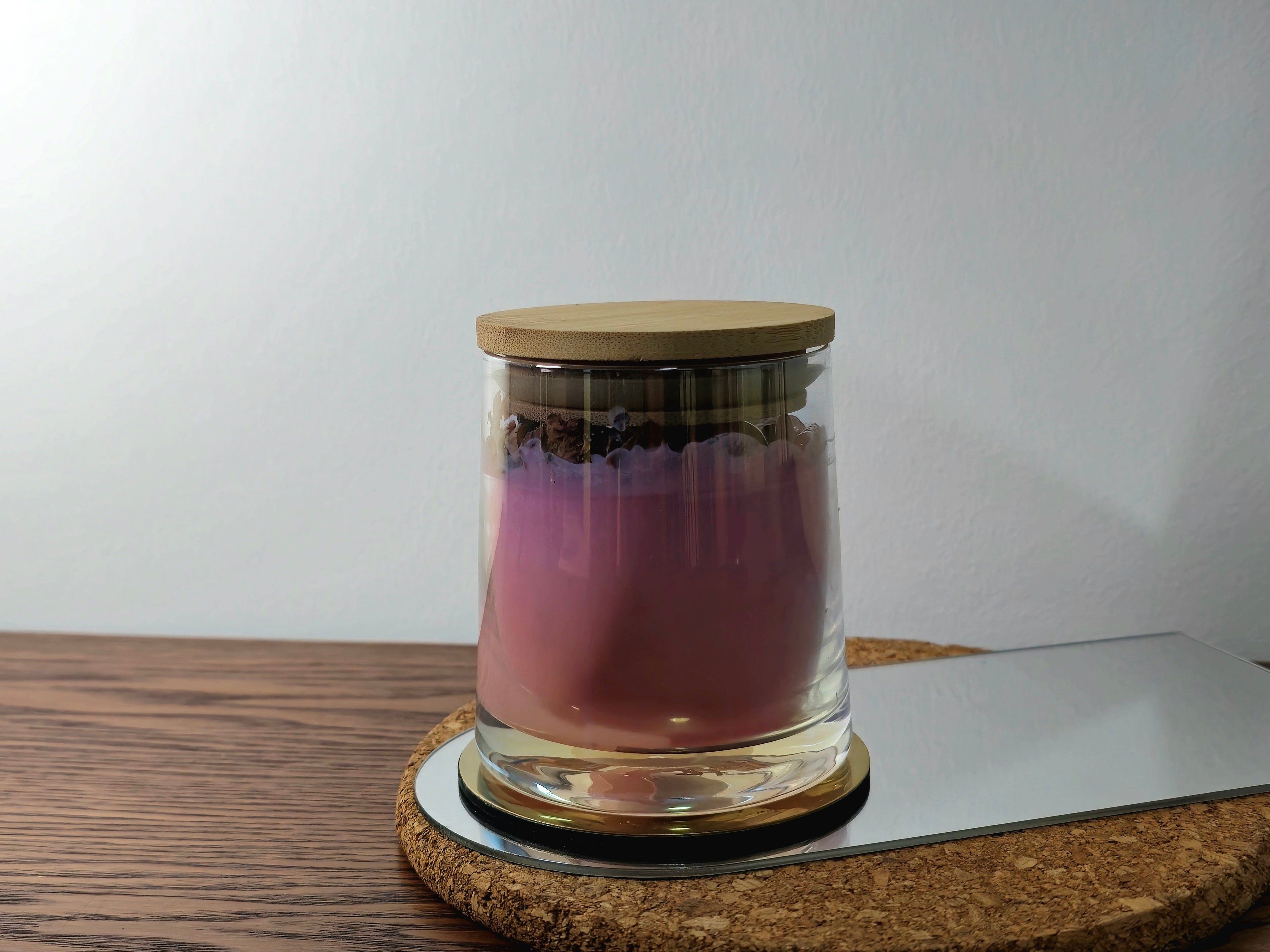 Candle Glass jar with a wooden lid on a cork coaster with a white background
