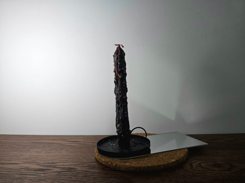 Decorated Candle on a black stand with a white plate on a wooden surface
