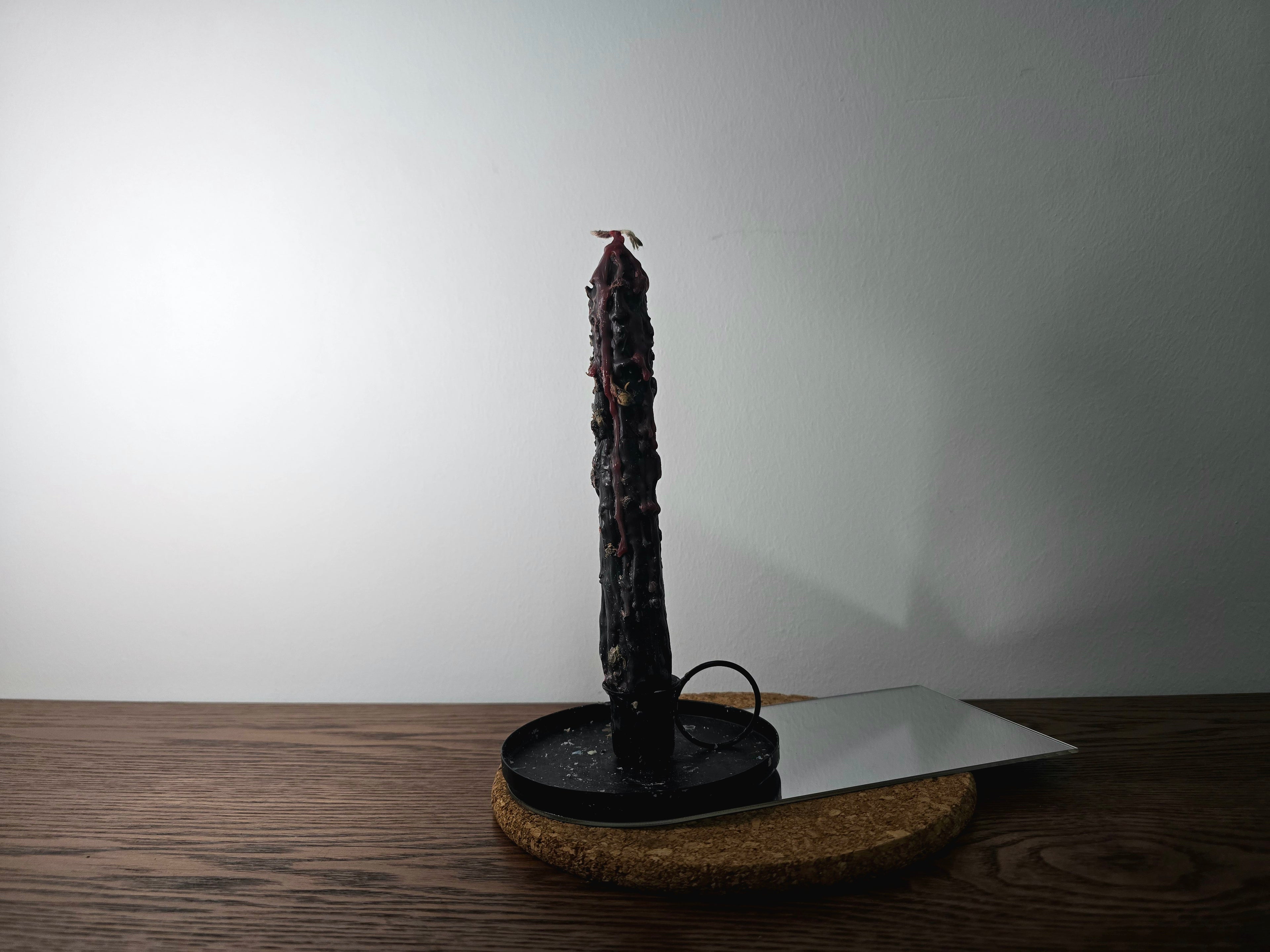 Decorated Candle on a black stand with a white plate on a wooden surface
